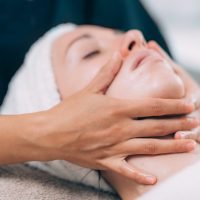 Facial Massage. Cosmetologist massaging young woman’s face.