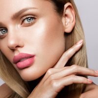 Beautiful young model with pink lips and nude manicure